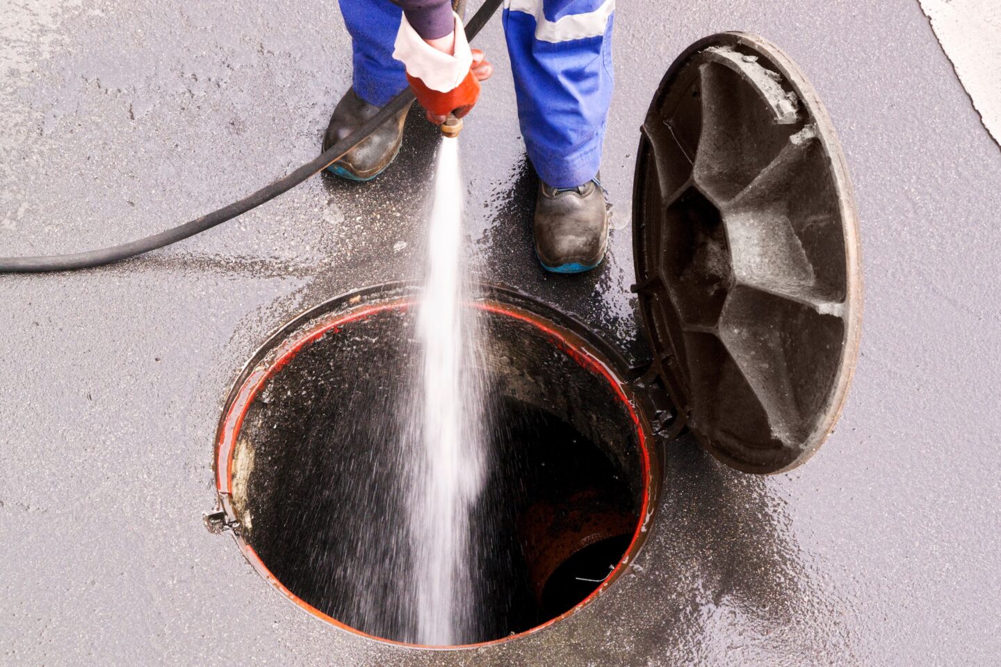 sewer line drainage by professional workers with hose and pressurized water of service truck