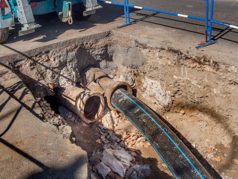 New plastic sewer pipe being inserted into a broken cast iron pipe.