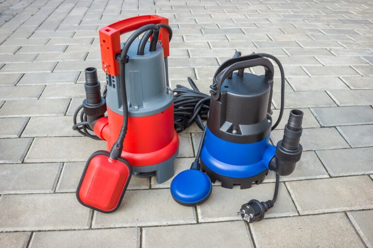Two household submersible pump with plastic housings on stone floor of courtyard