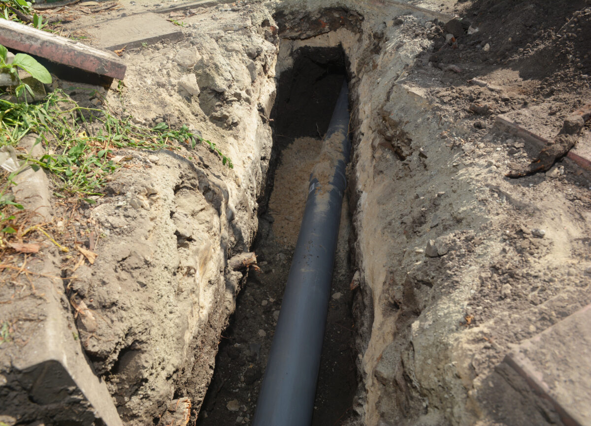 how deep are sewer lines buried Installing sewer pipe in the ground trench. House sewer drain pipe installation